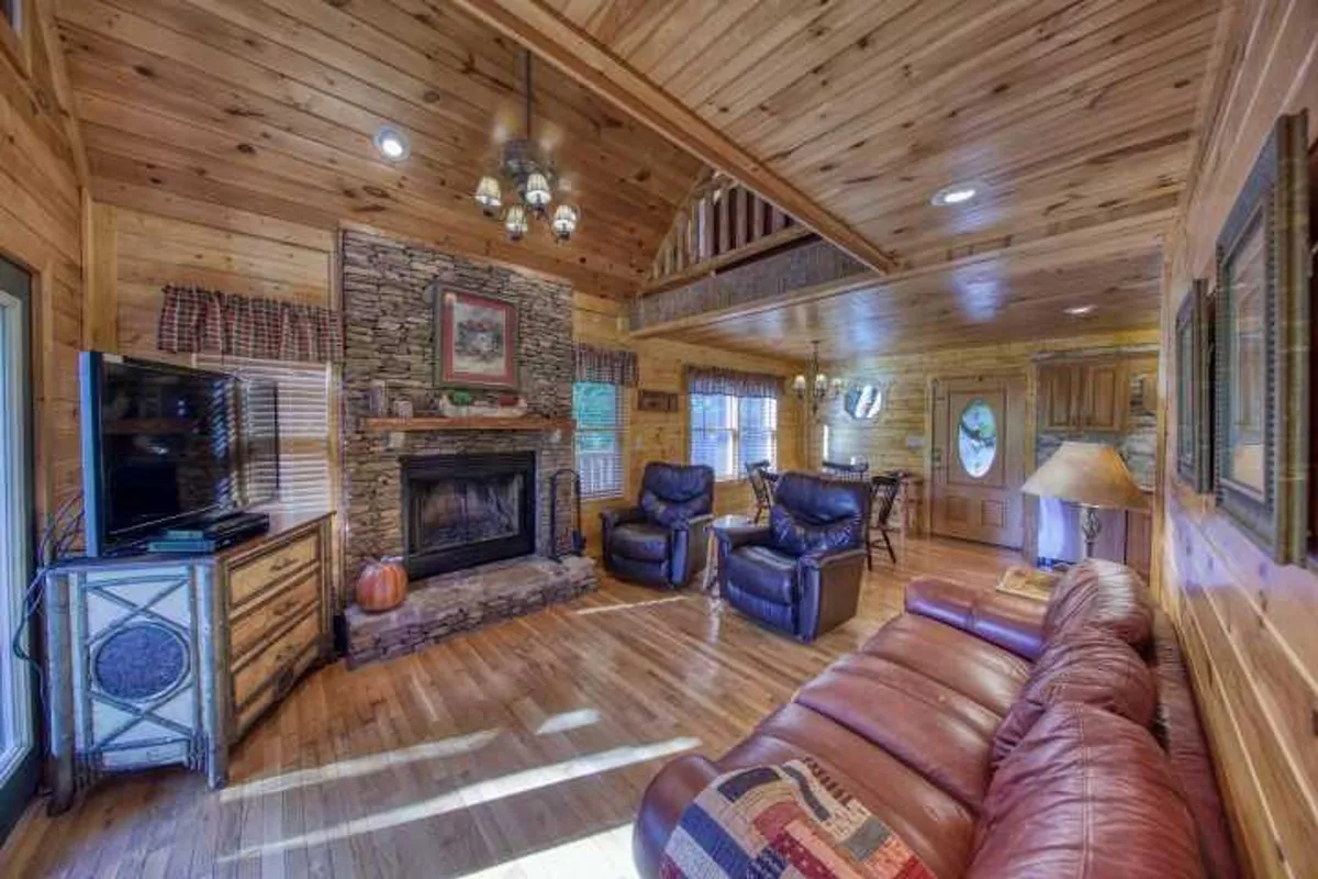 A cozy living area centered around a classic fireplace, with comfortable seating arranged for conversation or relaxation. Wooden walls and decorative lighting add to the room’s warmth and sense of retreat.